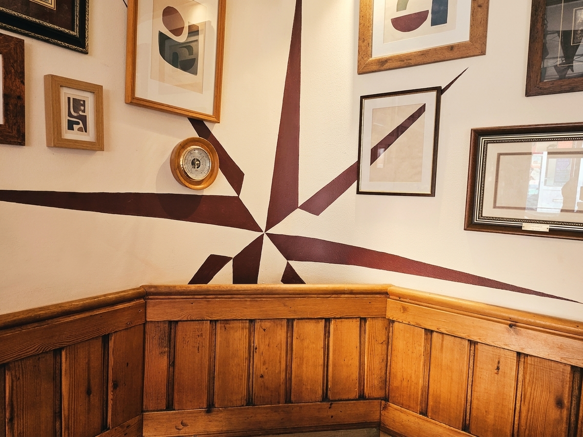 The pub's own compass-rose logo painted on the wall above the pine wainscoting