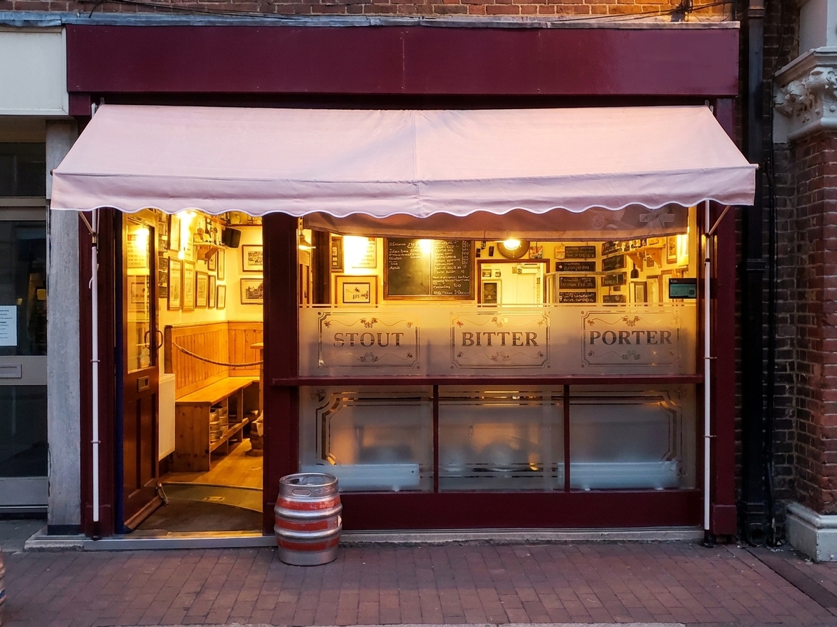 The Compass Alehouse shopfront on Manor Road: burgundy and cream, with etched STOUT, BITTER and PORTER windows